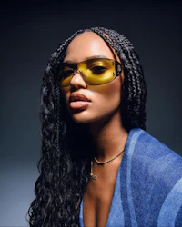 a black woman wearing sunglasses and a blue sweater